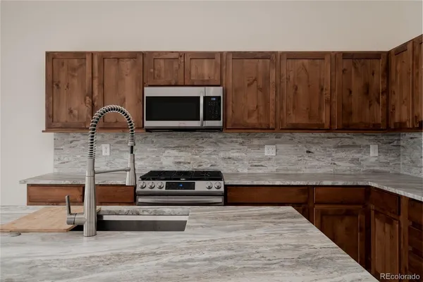 a kitchen with stainless steel appliances granite countertop a sink a microwave a stove and a refrigerator