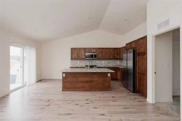 a large kitchen with stainless steel appliances granite countertop a stove and a refrigerator