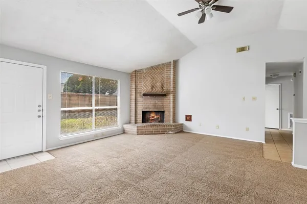 a view of an empty room with a fireplace and a window