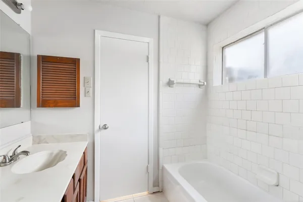 a bathroom with a tub a sink and a window