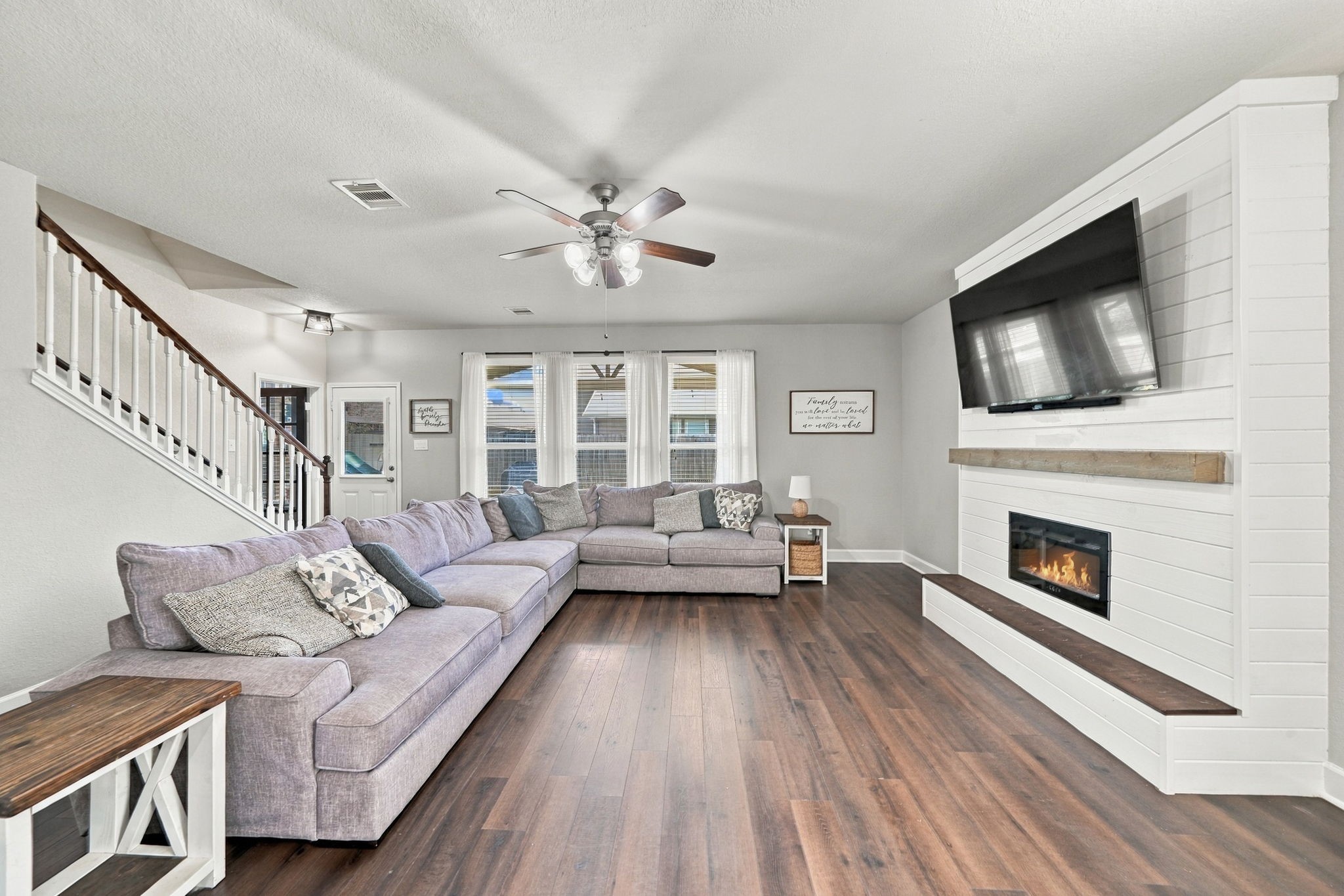 3406 Coopers Ridge Way Houston, TX 77084 - Photo 2 of 22 Living Room: Spacious living room filled with natural light and anchored by a striking fireplace feature wall, complemented by warm laminate flooring.