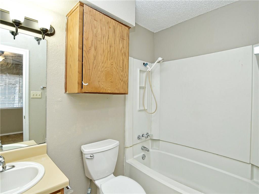 5401 Spring Meadow Road, Unit B Austin, TX 78744 - Photo 13 of 21 Functional bathroom features a combined tub and shower unit, complemented by a wall-mounted wooden cabinet.