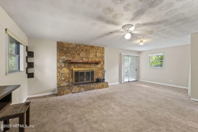 an empty room with windows and fireplace