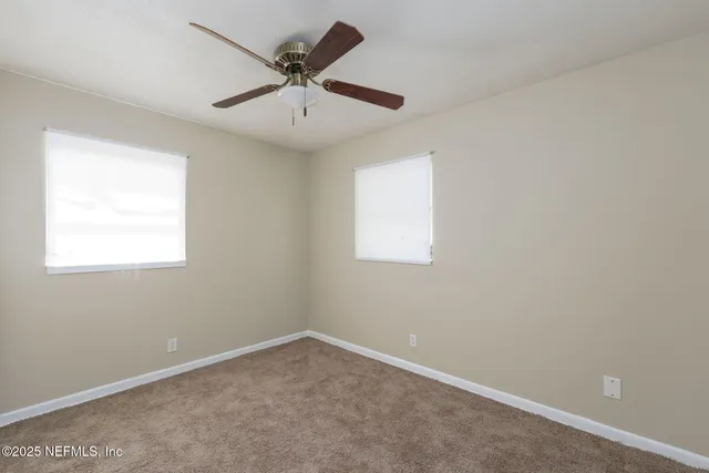 an empty room with a window and a fan