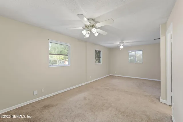 an empty room with windows and fan