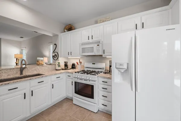 a kitchen with granite countertop white cabinets and stainless steel appliances