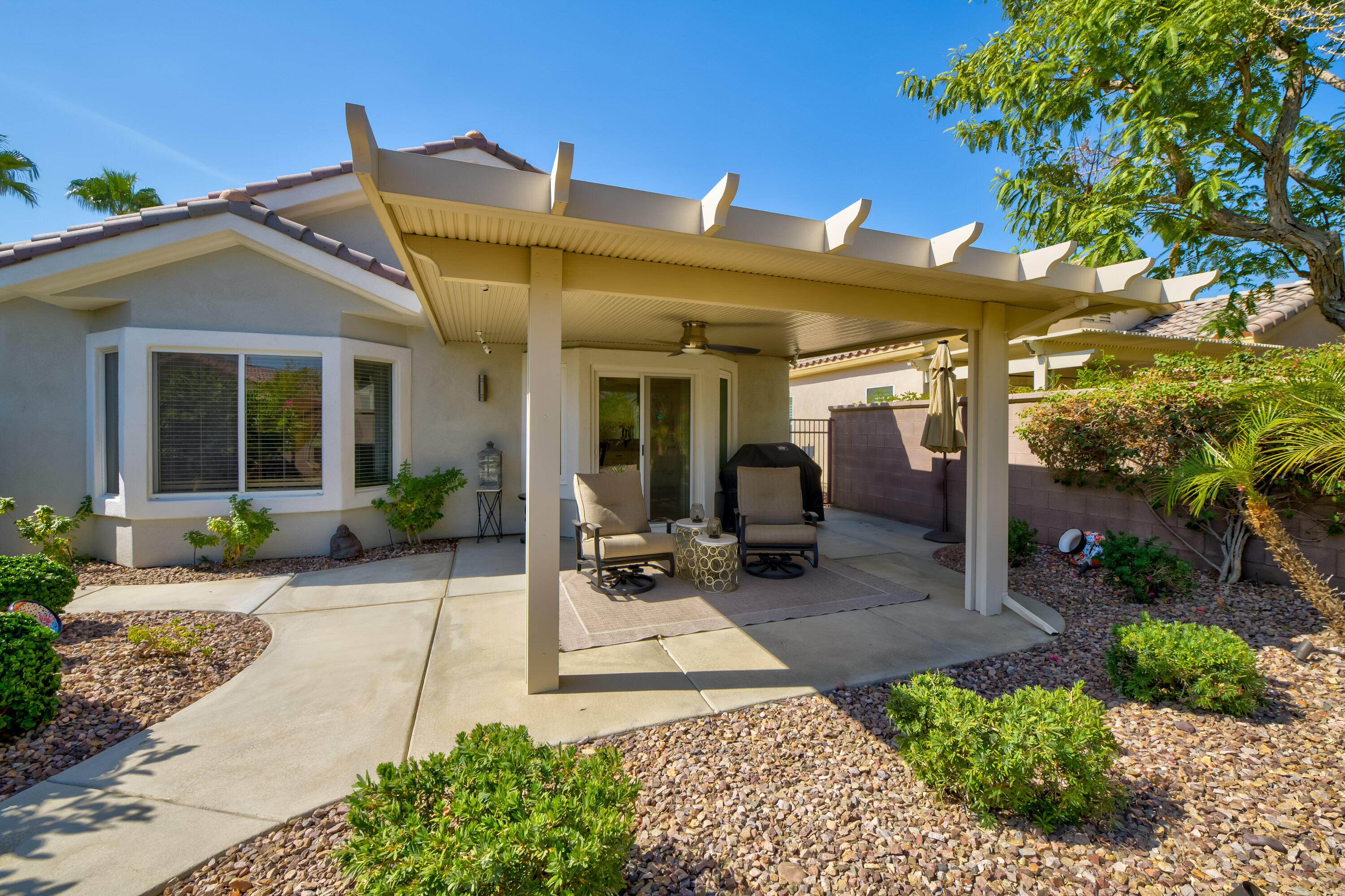 78680 Postbridge Circle Palm Desert, CA 92211 - Photo 25 of 54 a view of a patio with table and chairs potted plants and floor to ceiling window