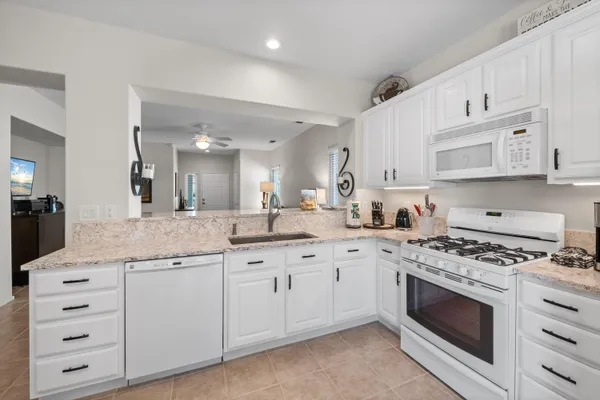 a kitchen with granite countertop white cabinets and white appliances