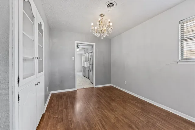 a view of a hallway with wooden floor and a chandelier