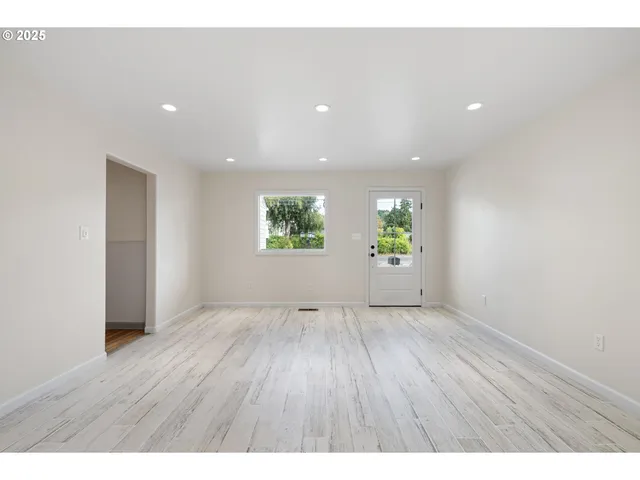 a view of an empty room with wooden floor and windows