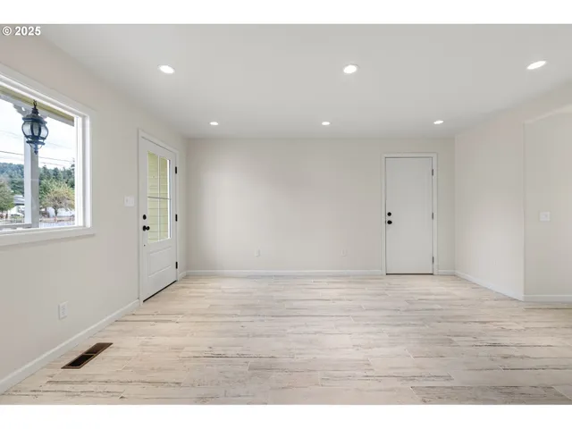 a view of an empty room with wooden floor and windows