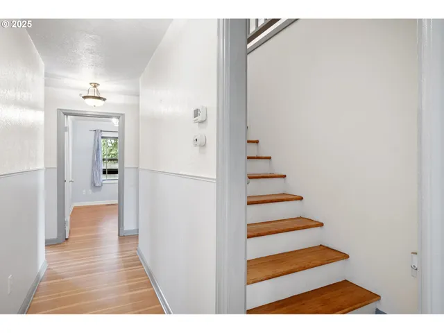 a view of a hallway with wooden floor and staircase