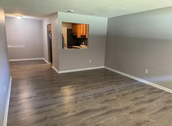 an empty room with wooden floor mirror and windows
