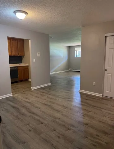 a view of empty room with kitchen and window
