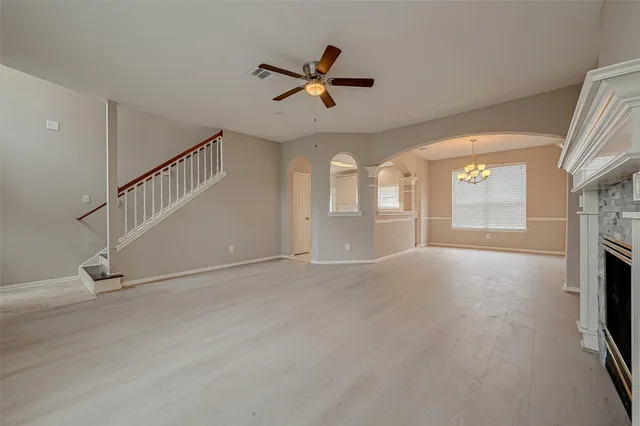 a view of an empty room with wooden floor fireplace and a window