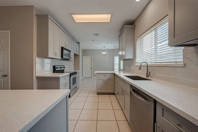 a kitchen with white cabinets appliances and a window