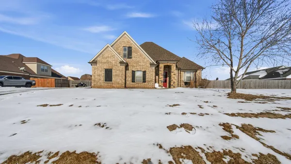 a front view of a house with a yard covered in snow