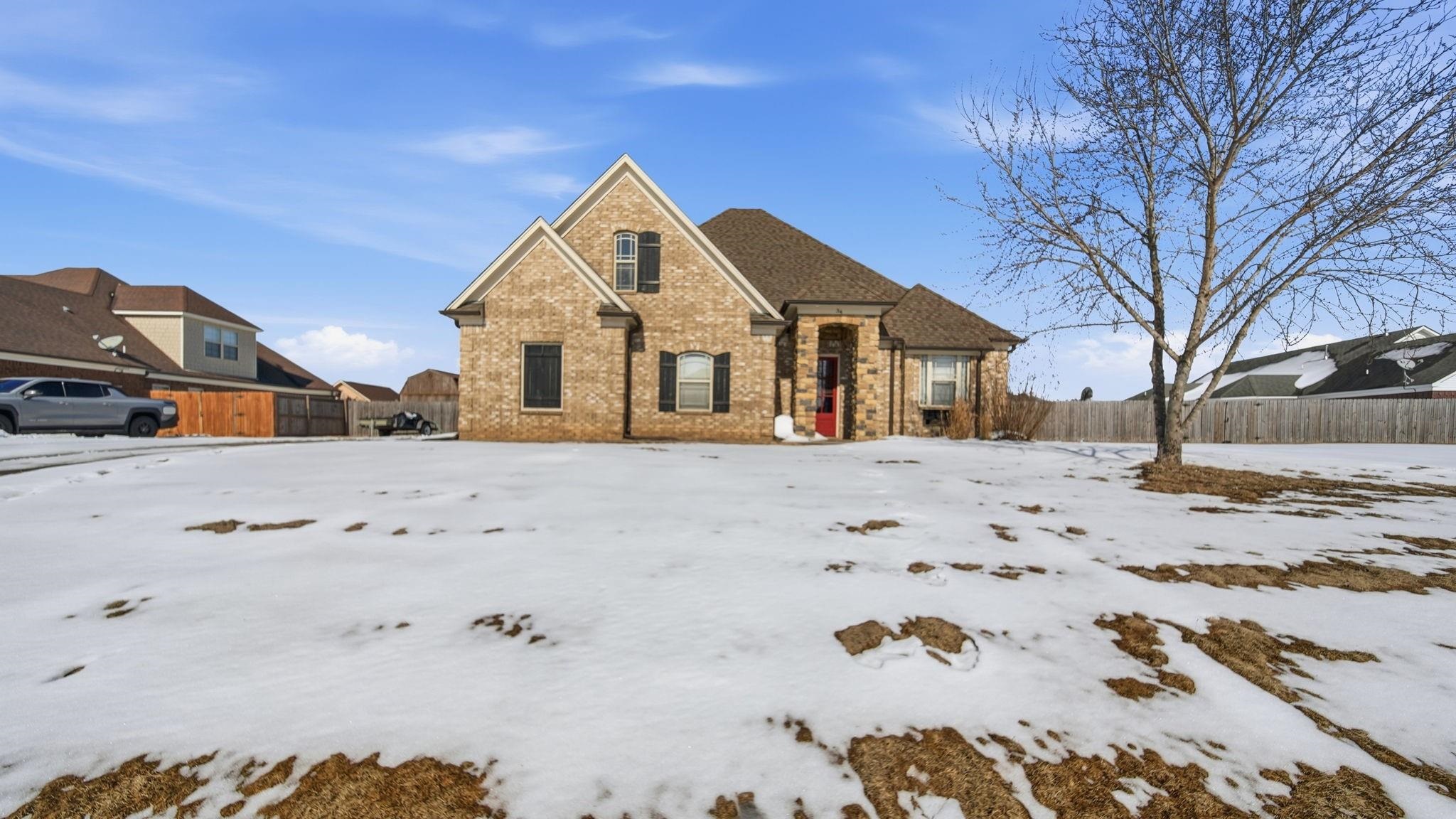 a front view of a house with a yard covered in snow