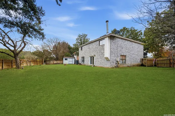 a view of a white house with a big yard and large trees
