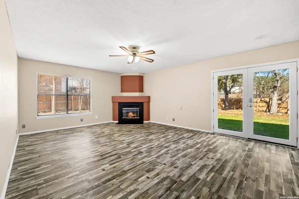 a view of an empty room with a window and wooden floor