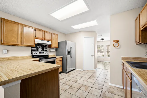 a kitchen with kitchen island granite countertop a refrigerator stove top oven and sink