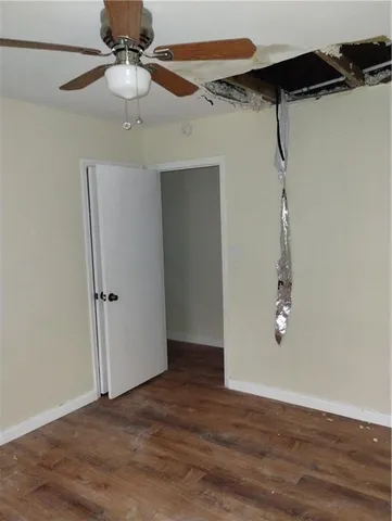 an empty room with wooden floor ceiling fan and window