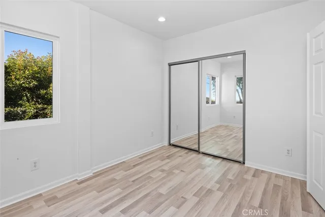 a view of a hallway with wooden floor and a bathroom