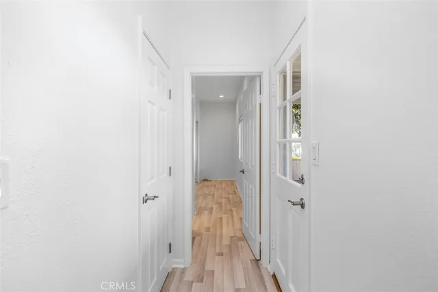 a view of a hallway with wooden floor and a bathroom