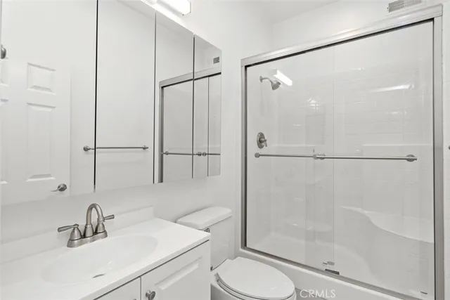 a bathroom with a shower sink vanity mirror and toilet