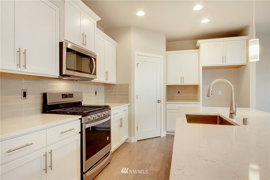 210 180th Place Southwest, Unit CT 01 Bothell, WA 98012 - Photo 8 of 19 a kitchen with stainless steel appliances granite countertop a stove a sink and a microwave