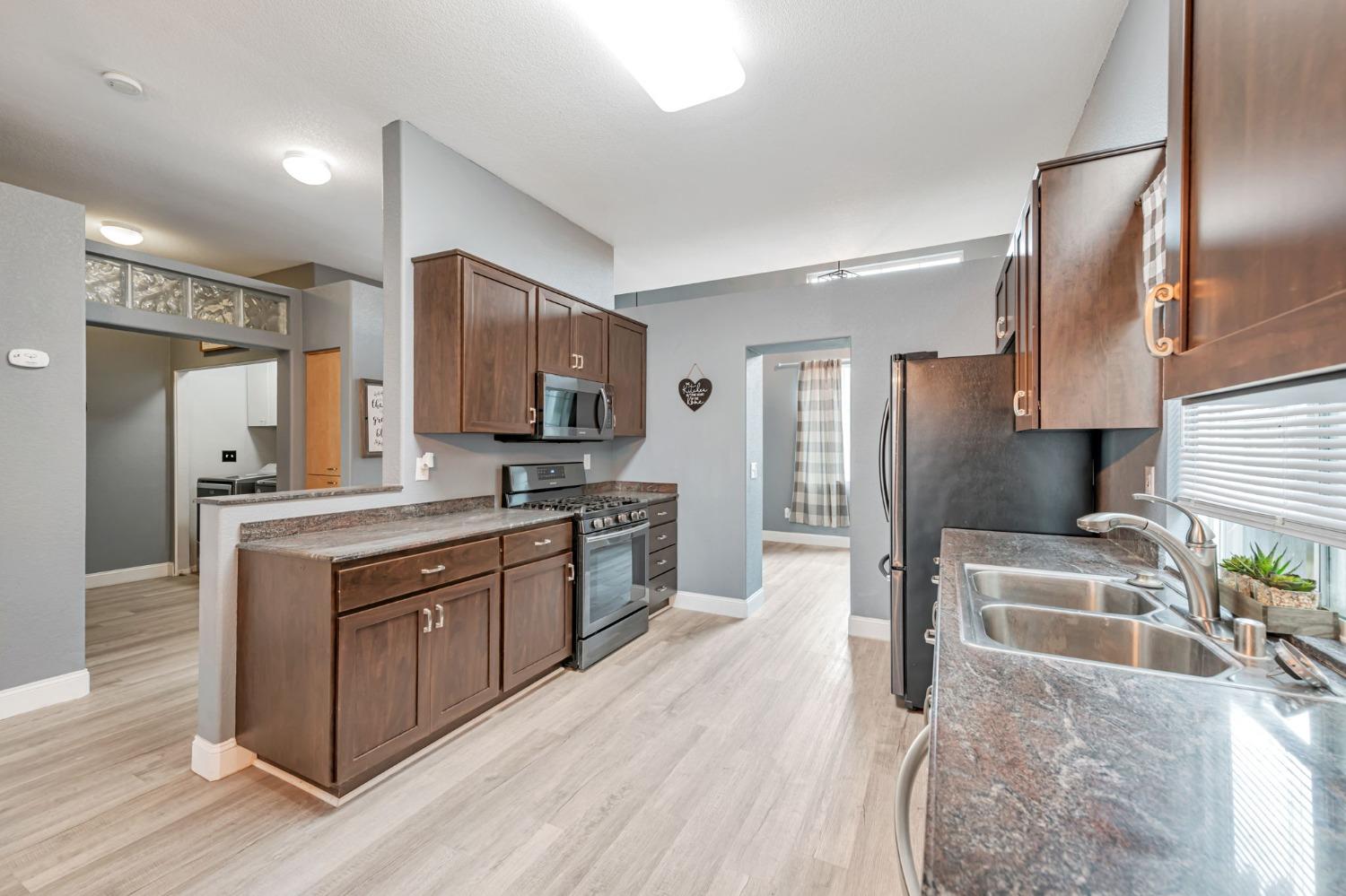 9065 Robbins Road Sacramento, CA 95829 - Photo 9 of 45 a kitchen with stainless steel appliances granite countertop a refrigerator a sink a stove and a wooden floors