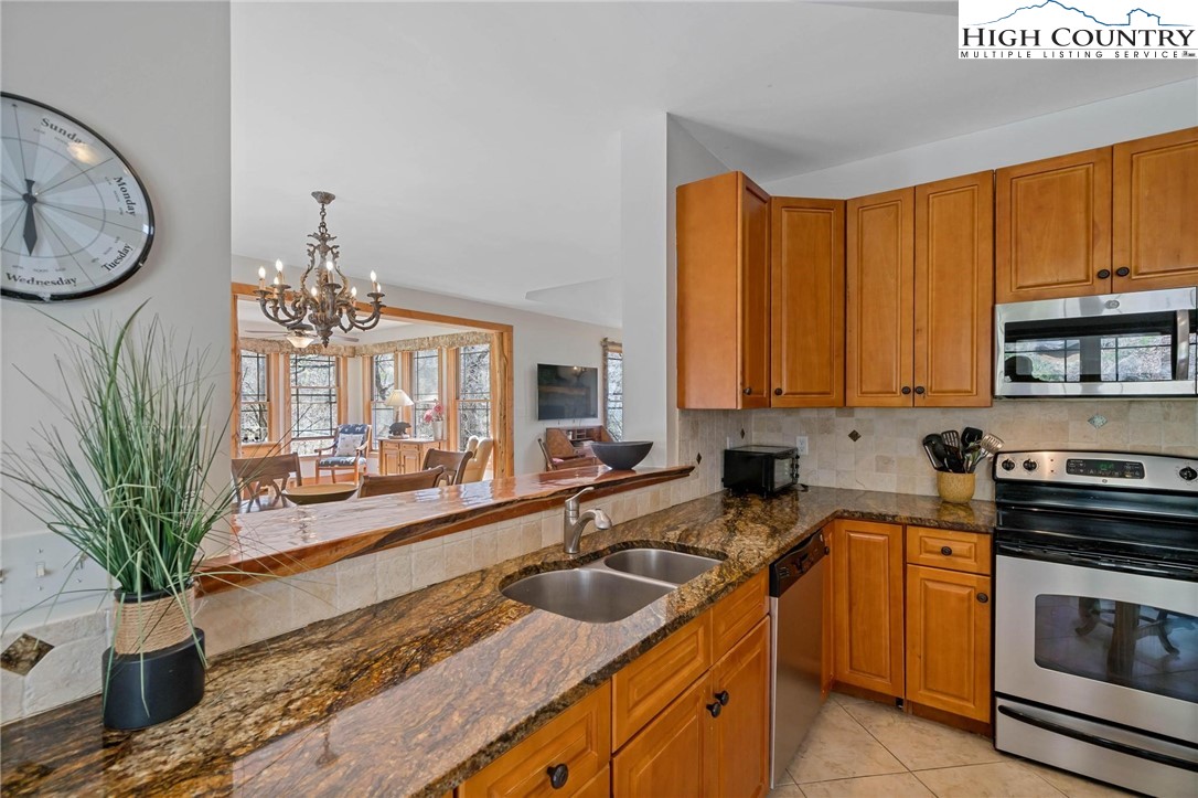 140 Spruce Hollow Road Beech Mountain, NC 28604 - Photo 12 of 50 a kitchen with stainless steel appliances granite countertop a sink a stove and a wooden floors