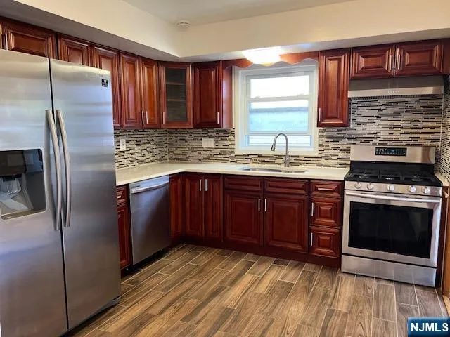 a kitchen with stainless steel appliances granite countertop a stove a sink dishwasher a refrigerator and wooden cabinets