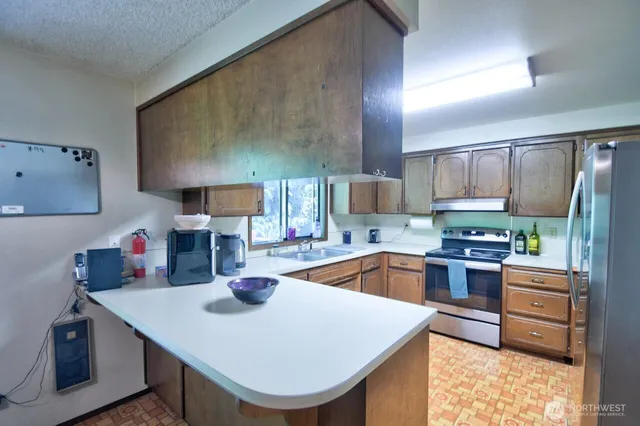 a kitchen with stainless steel appliances a sink a stove a refrigerator cabinets and wooden floor