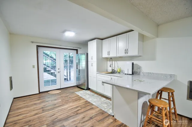 a kitchen with stainless steel appliances granite countertop a stove a sink and a refrigerator with wooden floor