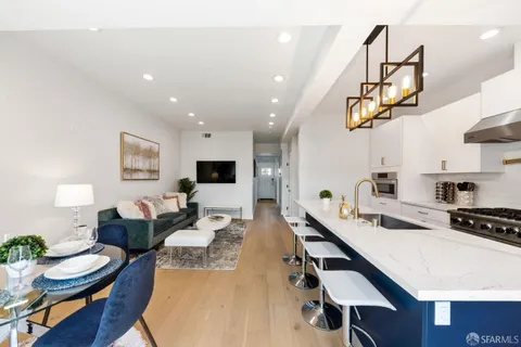 a living room with furniture kitchen view and a wooden floor