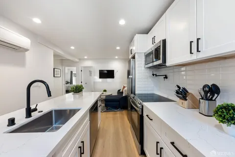 a kitchen with stainless steel appliances a sink dishwasher and white cabinets with wooden floor