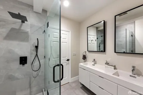 a bathroom with a double vanity sink mirror and shower