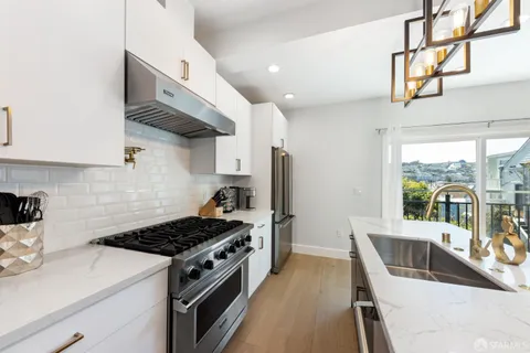 a kitchen with stainless steel appliances granite countertop a stove a sink dishwasher and refrigerator with wooden floor