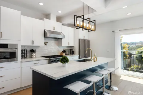 a kitchen with stainless steel appliances granite countertop a sink a stove a refrigerator and island with wooden floor