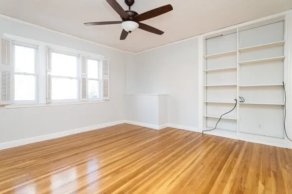 a view of an empty room with a window and wooden floor