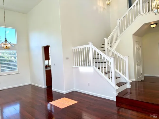a view of an empty room with wooden floor fireplace and a window