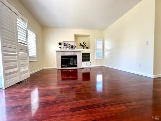 a view of empty room with wooden floor and fireplace