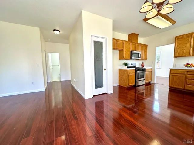 an empty room with wooden floor and windows with curtains