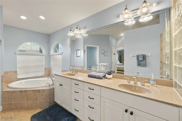 a bathroom with double vanity sink a bathtub and a window