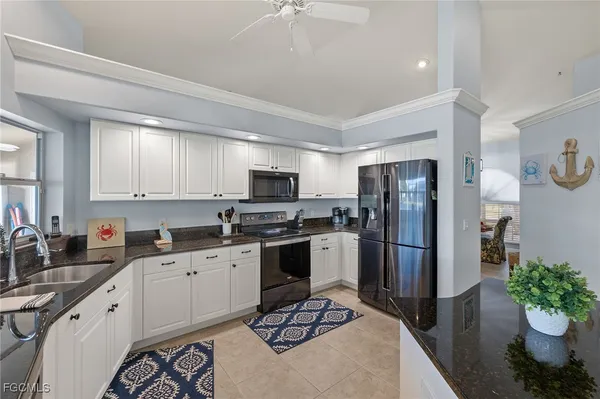 a kitchen with stainless steel appliances a sink a stove a refrigerator cabinets and a dining table