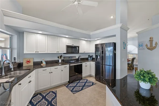 a kitchen with stainless steel appliances a sink a stove a refrigerator cabinets and a dining table