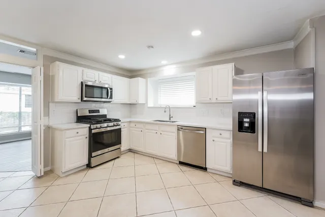 a kitchen with white cabinets stainless steel appliances and a window