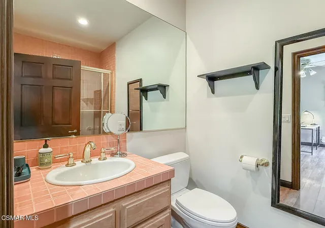 a bathroom with a toilet sink vanity granite and shower