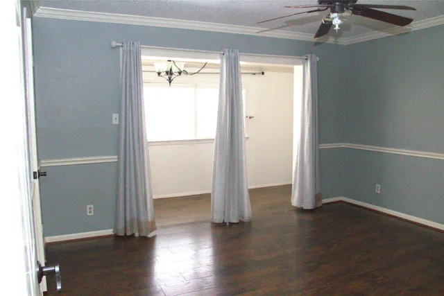 an empty room with wooden floor a ceiling fan and windows